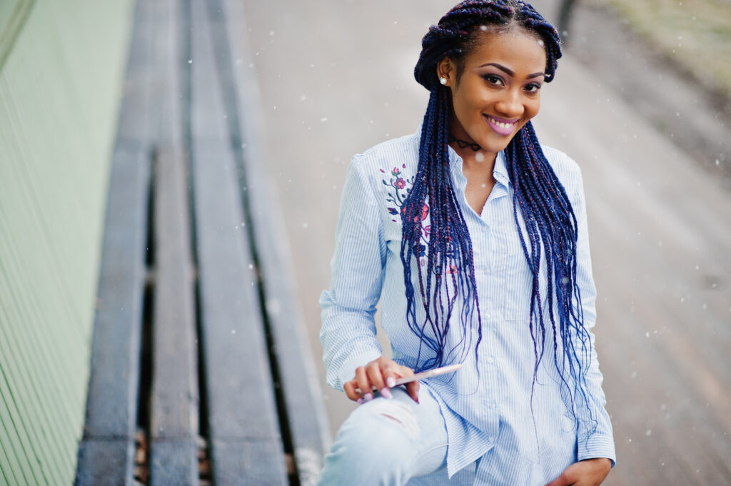 Woman confidently showing finished braids, highlighting benefits of braids maintenance Houston