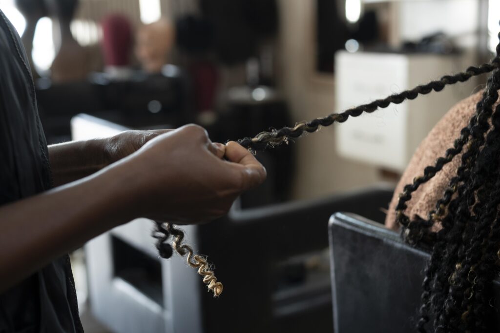 Stylist working on braids in Houston salon, showing professional braids maintenance Houston